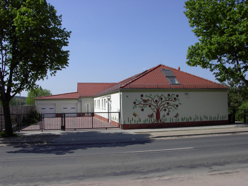 Neubau mit rotem Dach und Baummotiv an der Fassade